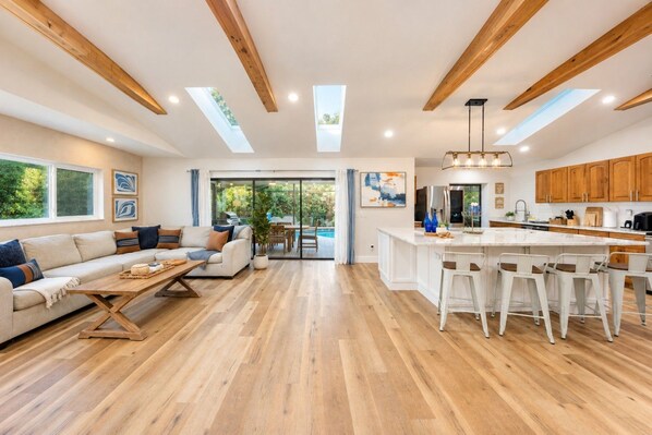 A spacious living area with a sofa, coffee table, and a view of a pool.