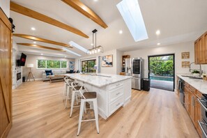 A modern kitchen with a central island, bar stools, a built-in oven, and a large refrigerator.