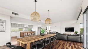 Une cuisine moderne avec des meubles blancs, un îlot central en bois et un coin repas comprenant une table en bois et des chaises noires.