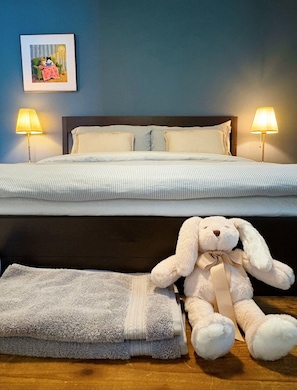 A neatly made bed with two pillows, a bedside lamp, a framed picture on the wall, and a plush toy on the floor. - Spacious 2BR by the Park • Large Backyard • Ideal for Families & Long Stays (Surrey)