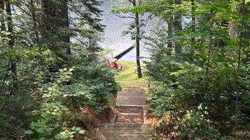 Una escalera de madera que conduce a una zona boscosa, con un lago al fondo.