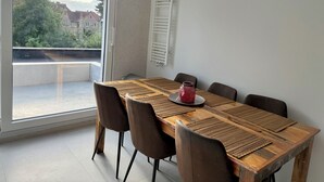 A dining area with a wooden table, brown chairs, and a red vase.