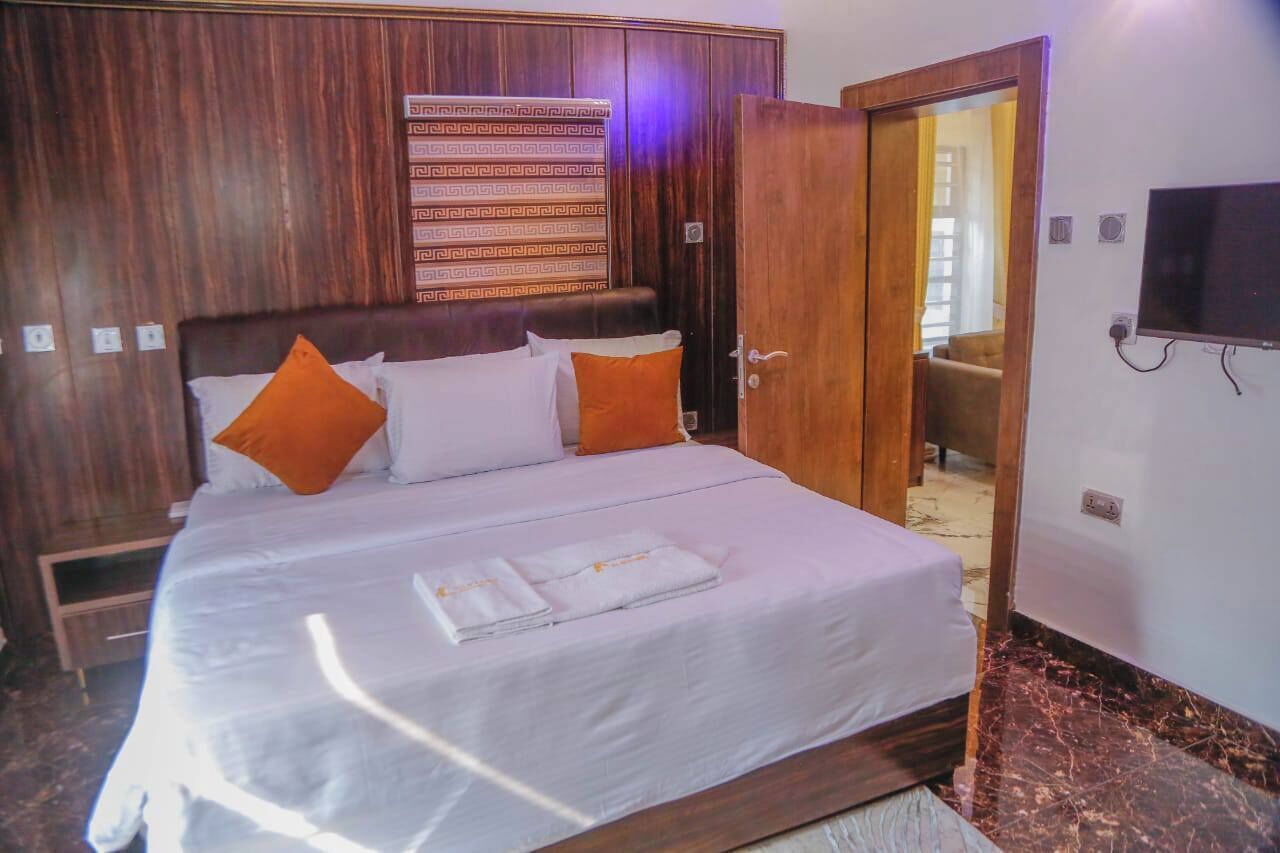 A hotel room with a large bed, wooden headboard, and a television on the wall.