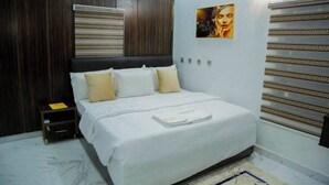 Ein Schlafzimmer mit einem großen Bett, einem Nachttisch, einem Wandregal und einer dekorativen Wandverkleidung.