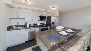 A modern kitchen with white cabinets, stainless steel appliances, and a central island with blue placemats. - Panoramic View and Free Parking (Honolulu)
