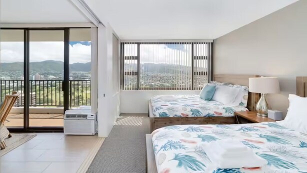A hotel room with a balcony, two beds, a desk, and a view of the city. - Panoramic View and Free Parking (Honolulu)