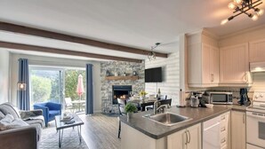 A modern kitchen with a stone backsplash, a built-in island, and a flat-screen TV above the counter.