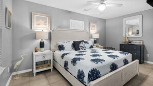 A bedroom with a bed, nightstands, a dresser, a ceiling fan, and wall-mounted artwork. - Cozy 1-bedroom condo in wonderful Destin with AC (Destin)