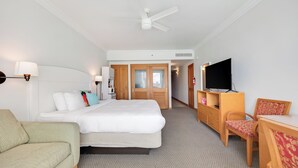 Une chambre d’hôtel équipée d’un lit, d’un bureau, d’une chaise, d’une télévision et d’un ventilateur de plafond.