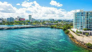 Un paysage urbain au bord de l’eau, avec des bâtiments modernes, un pont et une eau d’un bleu limpide.