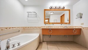 Une salle de bain moderne avec une grande baignoire, un meuble-lavabo en bois doté de deux vasques et un grand miroir au-dessus du meuble-lavabo.