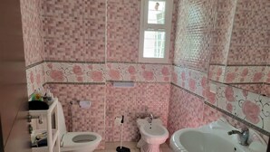 Une salle de bain équipée de toilettes, d’un bidet et d’un lavabo.
