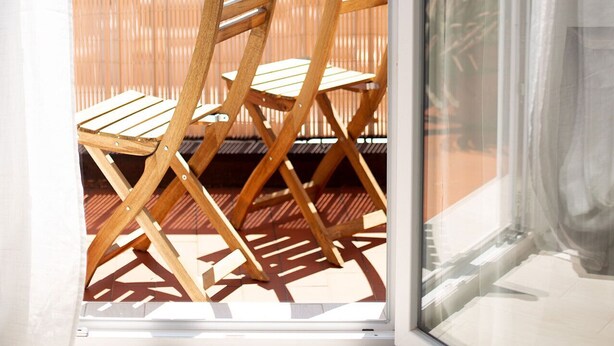 A balcony with two wooden chairs and a view of greenery and buildings in the distance. - Thomas House on Train Tracks (Venezia)