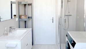 A modern bathroom with a white sink, mirror, and a glass-enclosed shower. - Thomas House on Train Tracks (Venezia)
