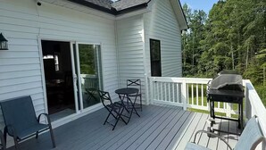 A deck with outdoor furniture, a grill, and a sliding glass door leading to an interior space.