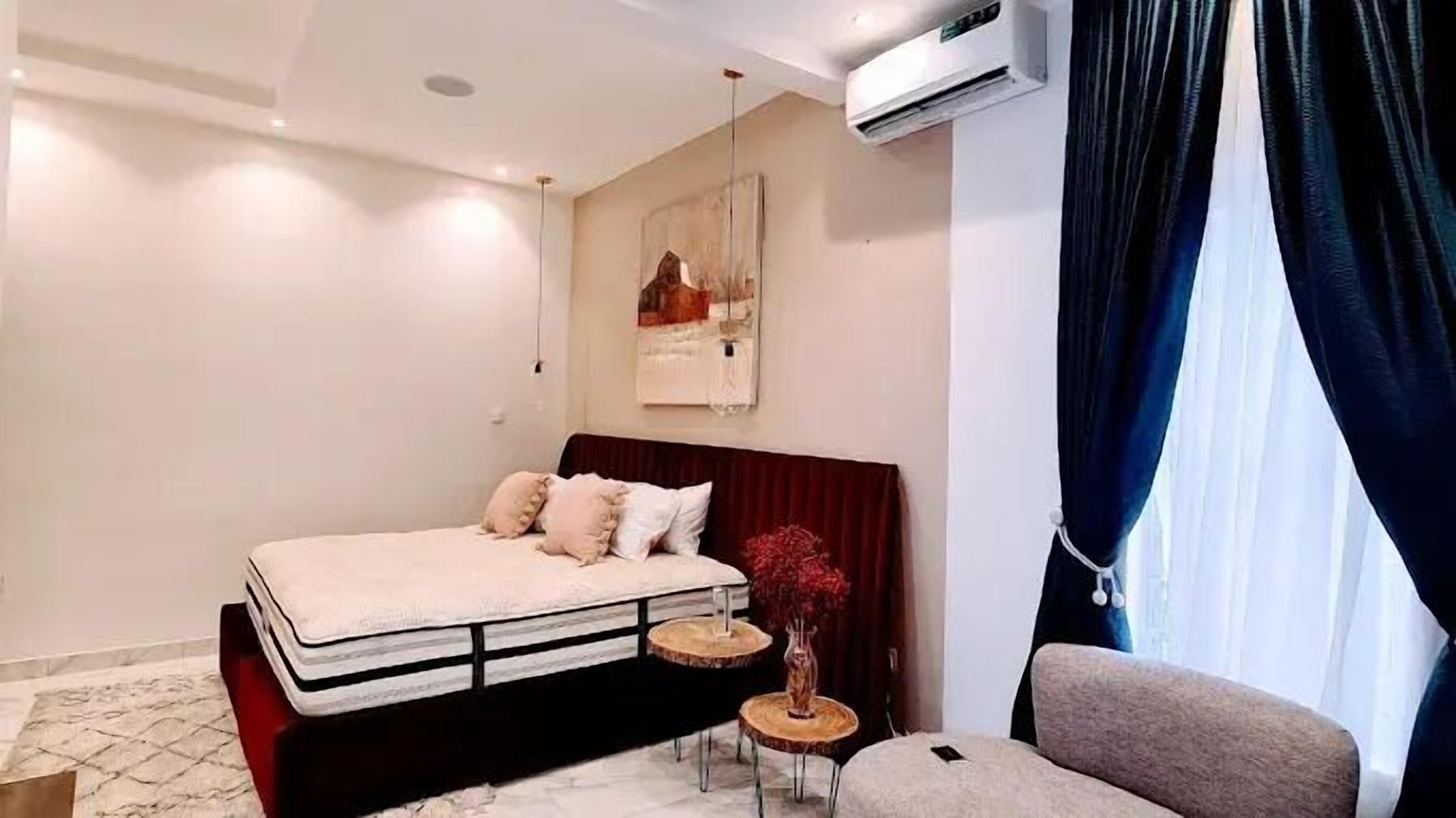 Une chambre moderne comprenant un lit, des tables de chevet, une chaise et un appareil de climatisation.