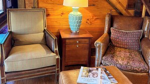 A wooden staircase, a wooden nightstand with a lamp, two upholstered chairs, and a leather ottoman with magazines. - The Bee Farm, House + Studio 15 Mins to Round Top (Ledbetter)