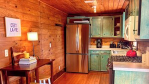A wooden interior with a kitchen area, including a refrigerator, stove, and wooden cabinets. - The Bee Farm, House + Studio 15 Mins to Round Top (Ledbetter)