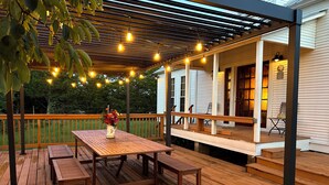 A wooden deck with a table and benches, string lights, and a covered area with a railing. - The Bee Farm, House + Studio 15 Mins to Round Top (Ledbetter)