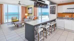 Et moderne hotelværelse med stor balkon, et tekøkken og et opholdsområde med havudsigt.