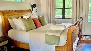 Un dormitorio con una cama de madera, una mesita de noche, una ventana con cortinas y un techo de madera.