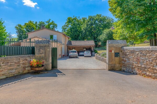 A gated entrance to a building with a garage, two parked cars, and a stone wall on one side.