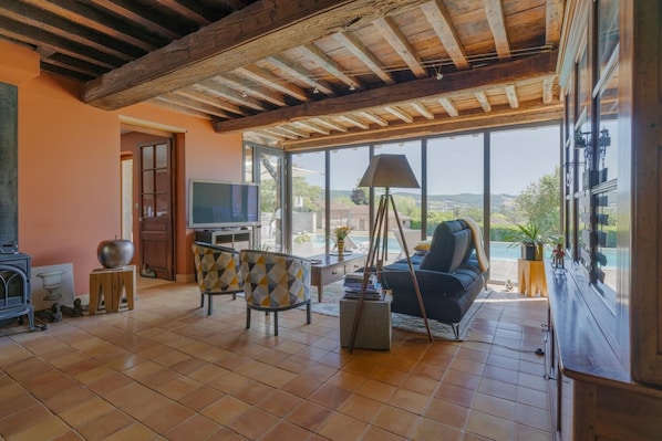 A spacious living room with a fireplace, a television, and a large window offering a view of the outdoors. - Le Clos des Acacias - CLUNY (CLUNY)