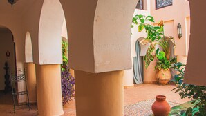 A courtyard with arches, potted plants, and a tiled floor. - Riad Dar Lalla (Marrakech)