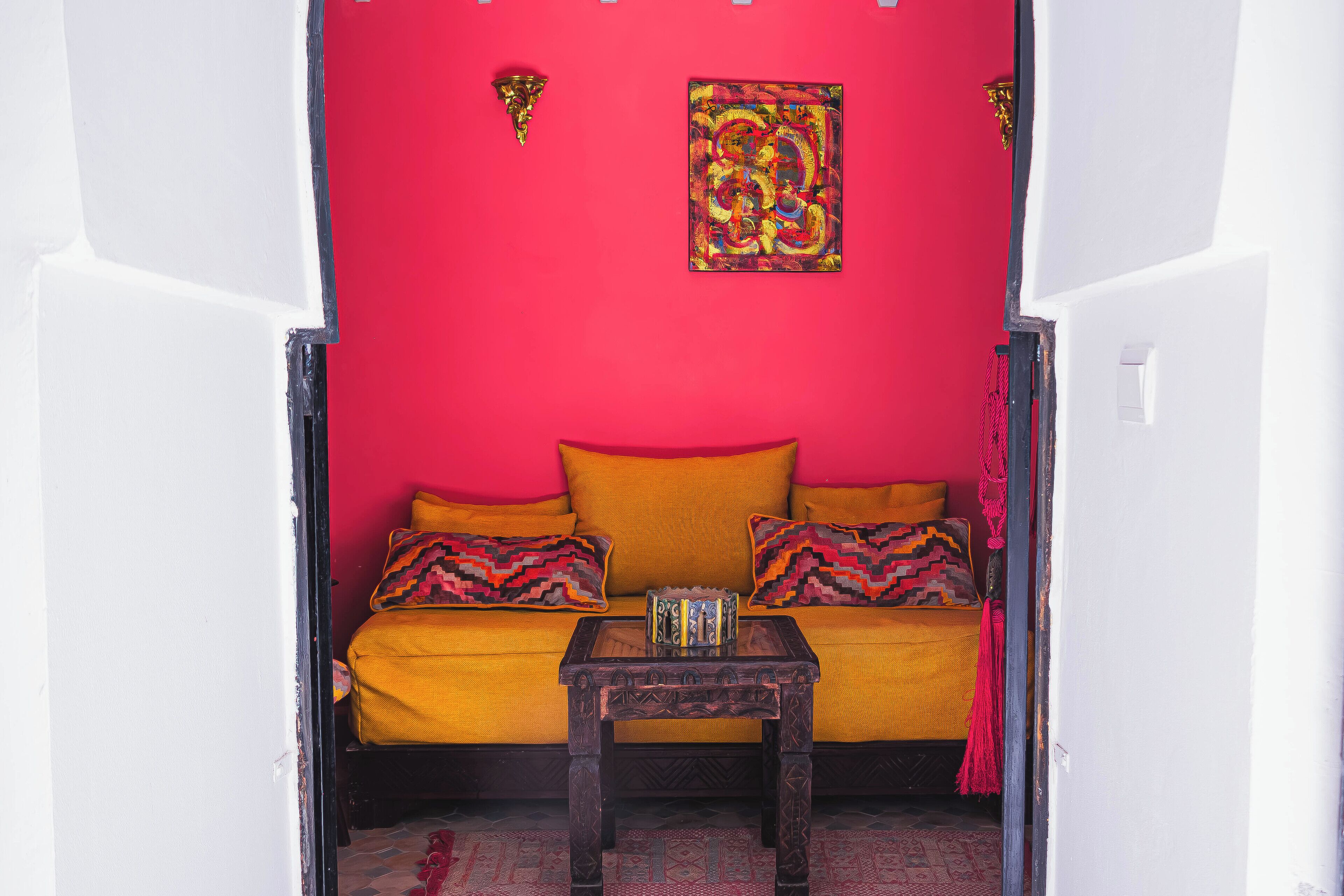 Ein Zimmer mit roter Wand, gelbem Sofa und einem kleinen Holztisch.
