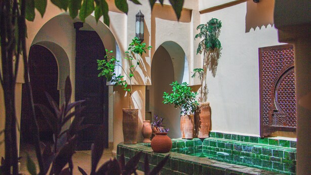 A courtyard with arches, potted plants, and a tiled floor. - Riad Dar Lalla (Marrakech)