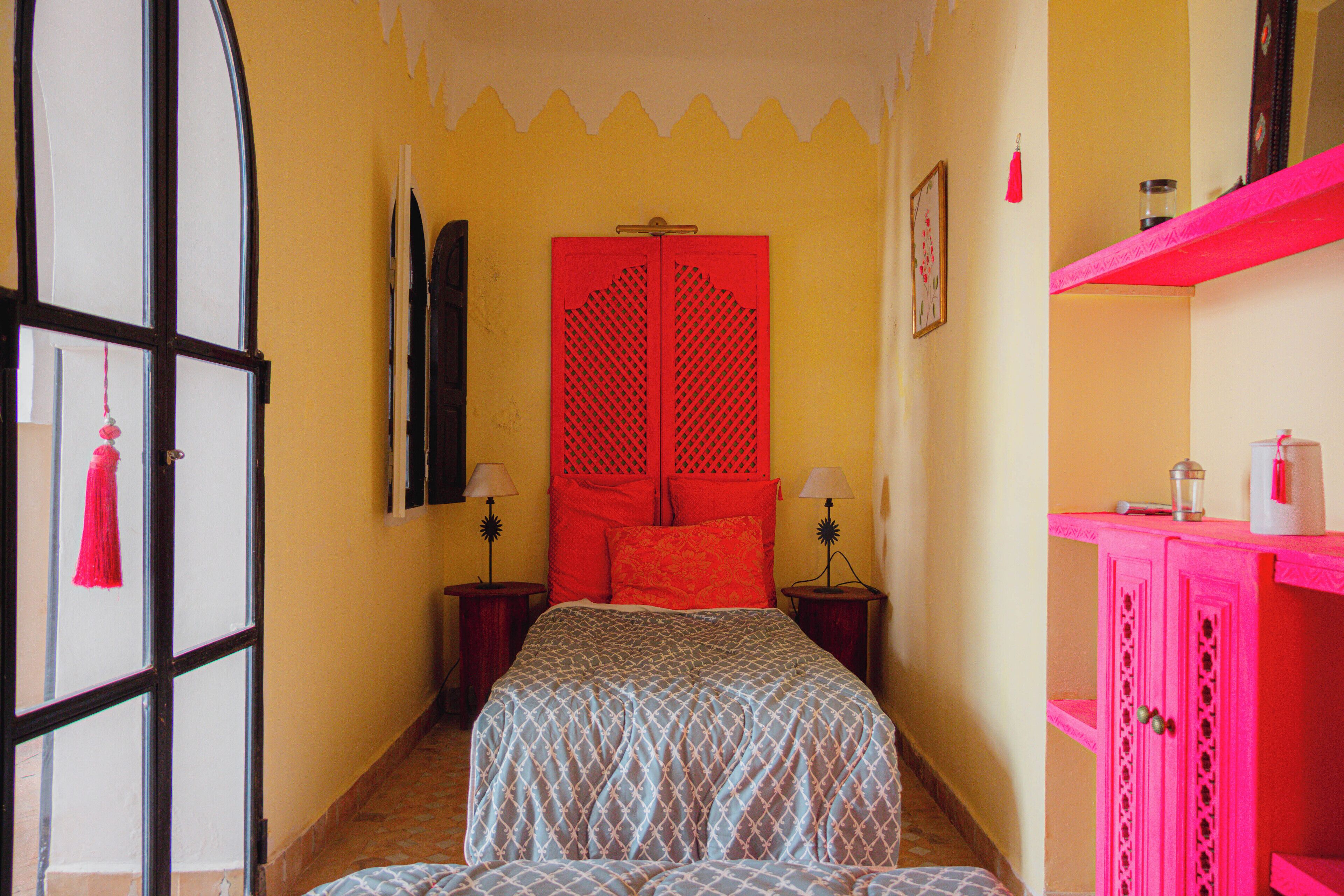 A bedroom with a bed, a wardrobe, a mirror, and a door.