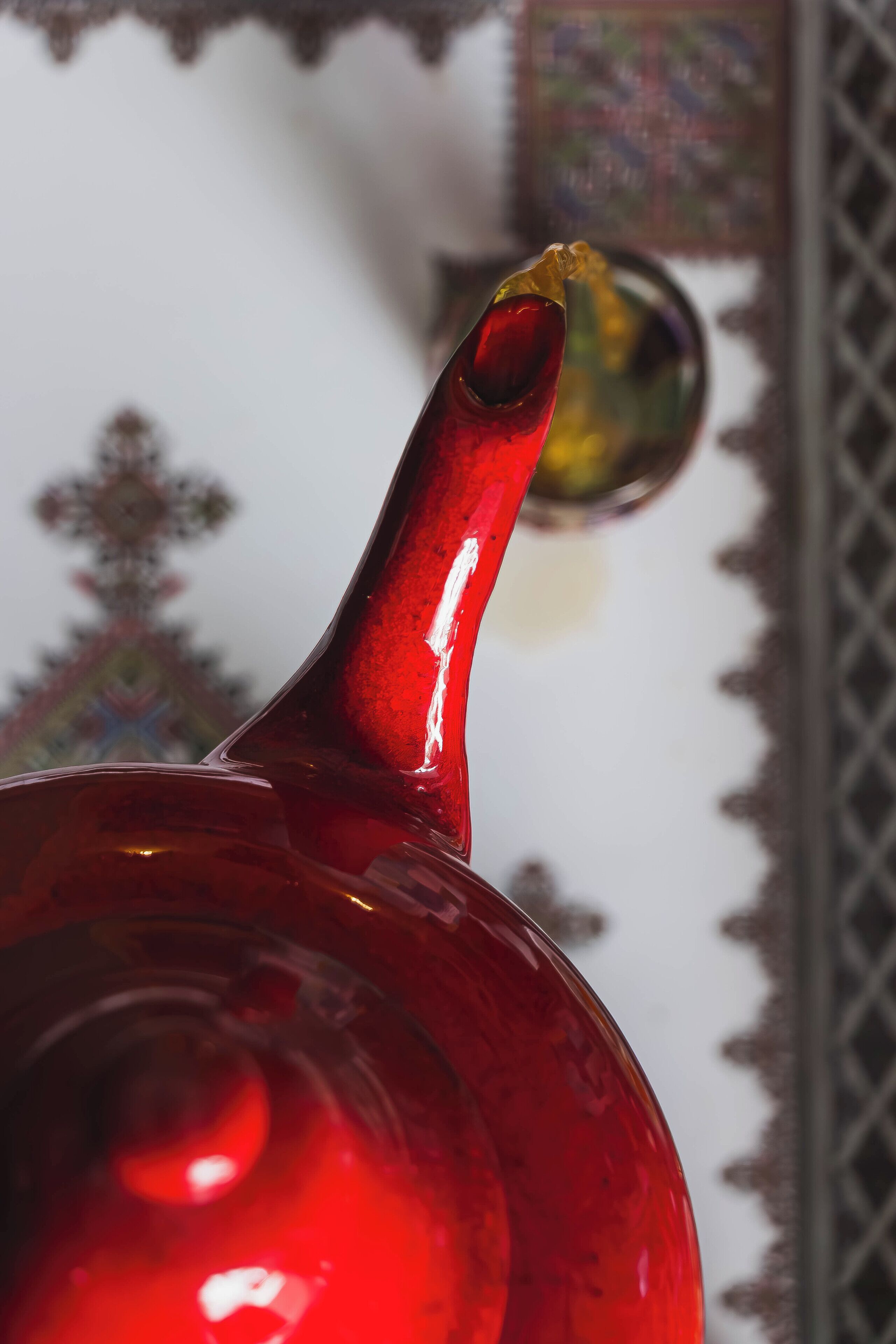 Um objeto de vidro vermelho, com gola estreita e base mais larga, possivelmente um item decorativo.