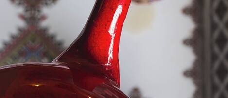 Um objeto de vidro vermelho, com gola estreita e base mais larga, possivelmente um item decorativo.