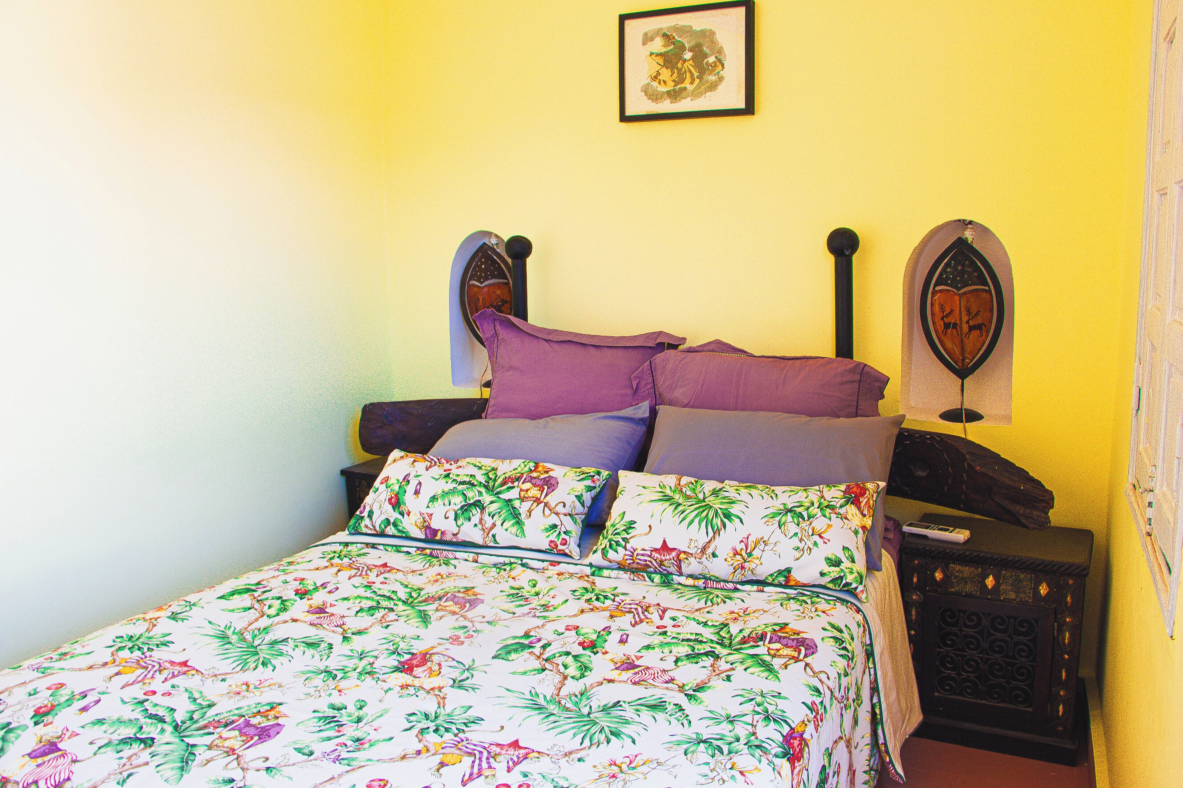 A bed with floral bedding, a headboard with a crest, and a nightstand with a lamp.