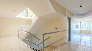 A spacious interior with a staircase, a fire extinguisher, and a window with bars. - Cozy Studio in Asa Norte BSB Esz0103 (Brasília)