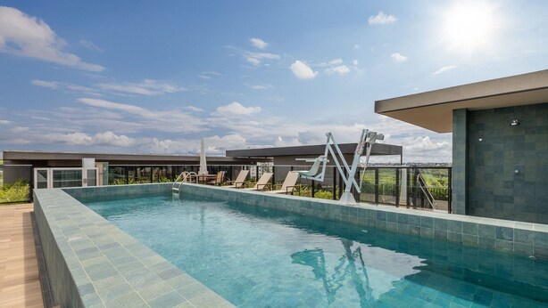 A modern outdoor swimming pool with a clear blue sky, lounge chairs, and a water slide. - Comfort and Convenience in Brasilia - Get0302 (Guará)