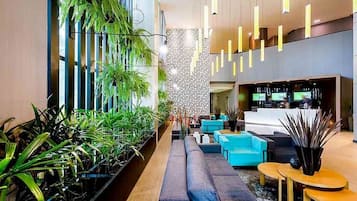 Um lobby moderno com um longo banco, área de estar e um balcão de recepção.
