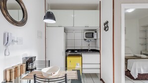 A compact hotel room with a kitchenette, a bed, a dining area, and a bathroom. - Charming Apartment in Asa Norte, Brasilia Gpk0115 (Brasília)