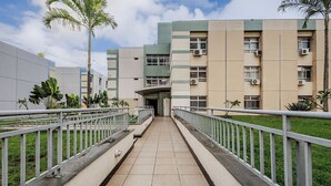 A pathway leading to a building with multiple windows and air conditioning units, surrounded by greenery and a clear sky. - Charming Apartment in Asa Norte, Brasilia Gpk0115 (Brasília)