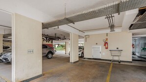 A parking garage with concrete floors, a fire extinguisher, and a metal rack. - Charming Apartment in Asa Norte, Brasilia Gpk0115 (Brasília)