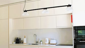 Une cuisine moderne avec des meubles blancs, un îlot central doté de tabourets, un four Bosch et des luminaires suspendus.