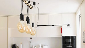 Une cuisine moderne avec des meubles blancs, un îlot central et des luminaires suspendus.