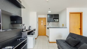 A modern kitchen with a microwave, toaster, and coffee maker. There is a black sofa and a wooden door in the living area. - Beautiful Studios in Condominium With Pool - Aguas Claras - Madb (Águas Claras)
