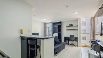 Un espacio habitable compacto con kitchenette, un sofá, una mesa de comedor y un televisor.