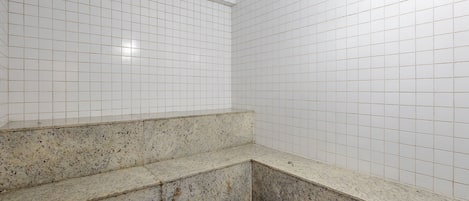 A bathroom with white tiled walls and a granite countertop.