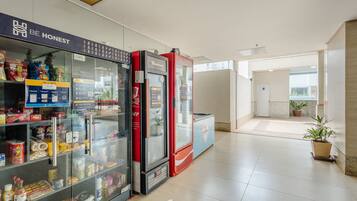 A hallway with vending machines stocked with snacks and beverages, a sign that says "BE HONEST", and a potted plant in the distance.