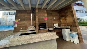 A modern building with a rooftop bar area featuring a grill, seating, and a view of the cityscape. - Beautiful Studios in Condominium With Pool - Aguas Claras - Madb (Águas Claras)