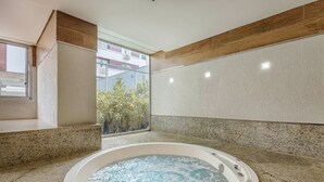 A spa area with a hot tub, granite countertops, and a view of a building with balconies. - Beautiful Studios in Condominium With Pool - Aguas Claras - Madb (Águas Claras)