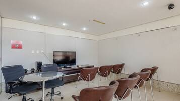 Una sala de conferencias con una mesa redonda, varias sillas, un televisor y un sistema de sonido.