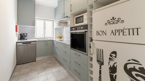 A modern kitchen with grey cabinets, a built-in oven, microwave, and a dishwasher.